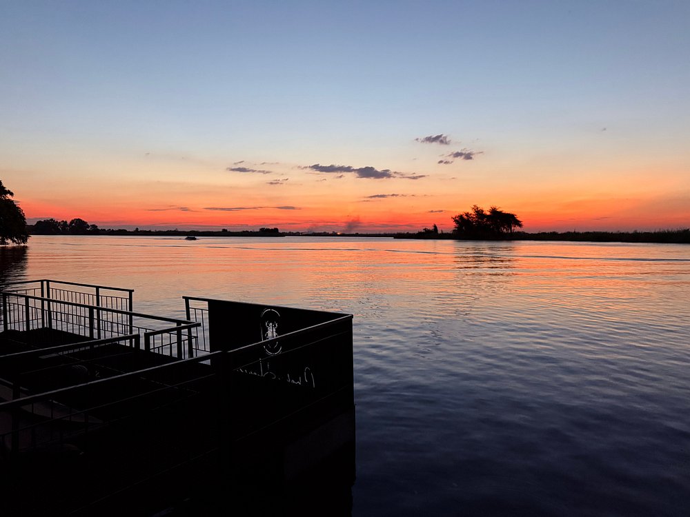 Chobe river sunset — vivid orange sky reflected on still water